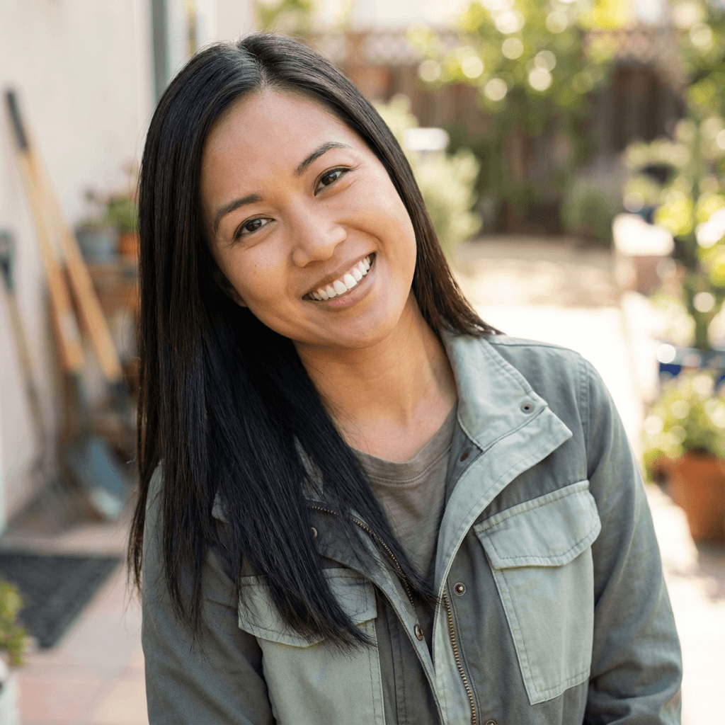 Angela Ruiz, a warm smiling woman in her 40s in her backyard